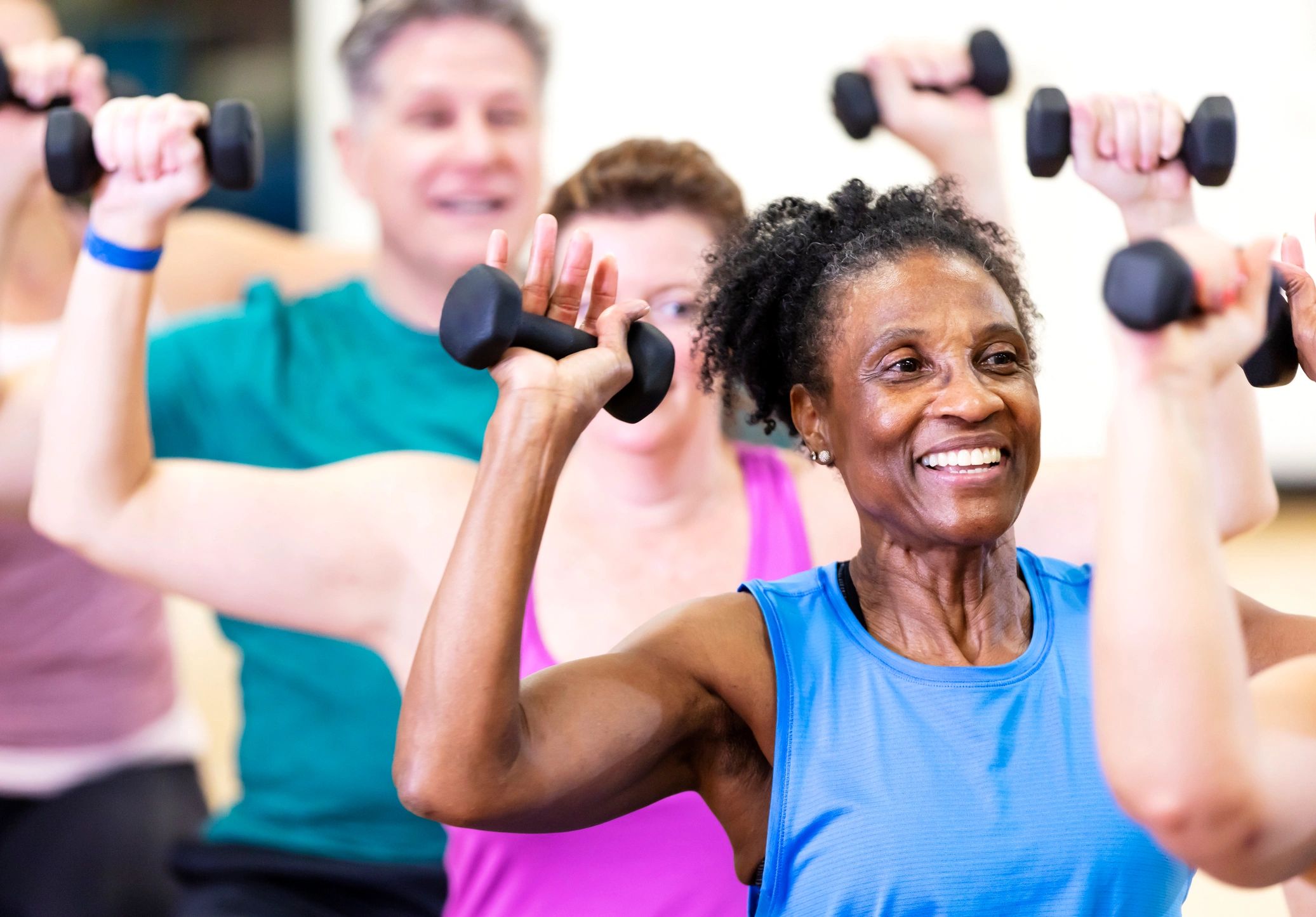 Senior woman lifting hand weights in a group fitness class