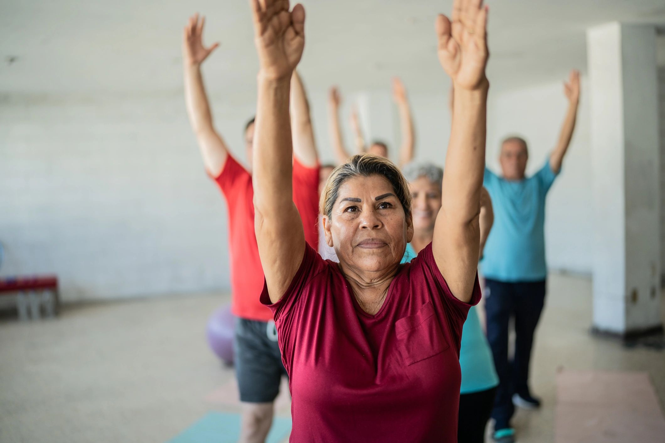 Senior woman stretching with classmates in a studio
