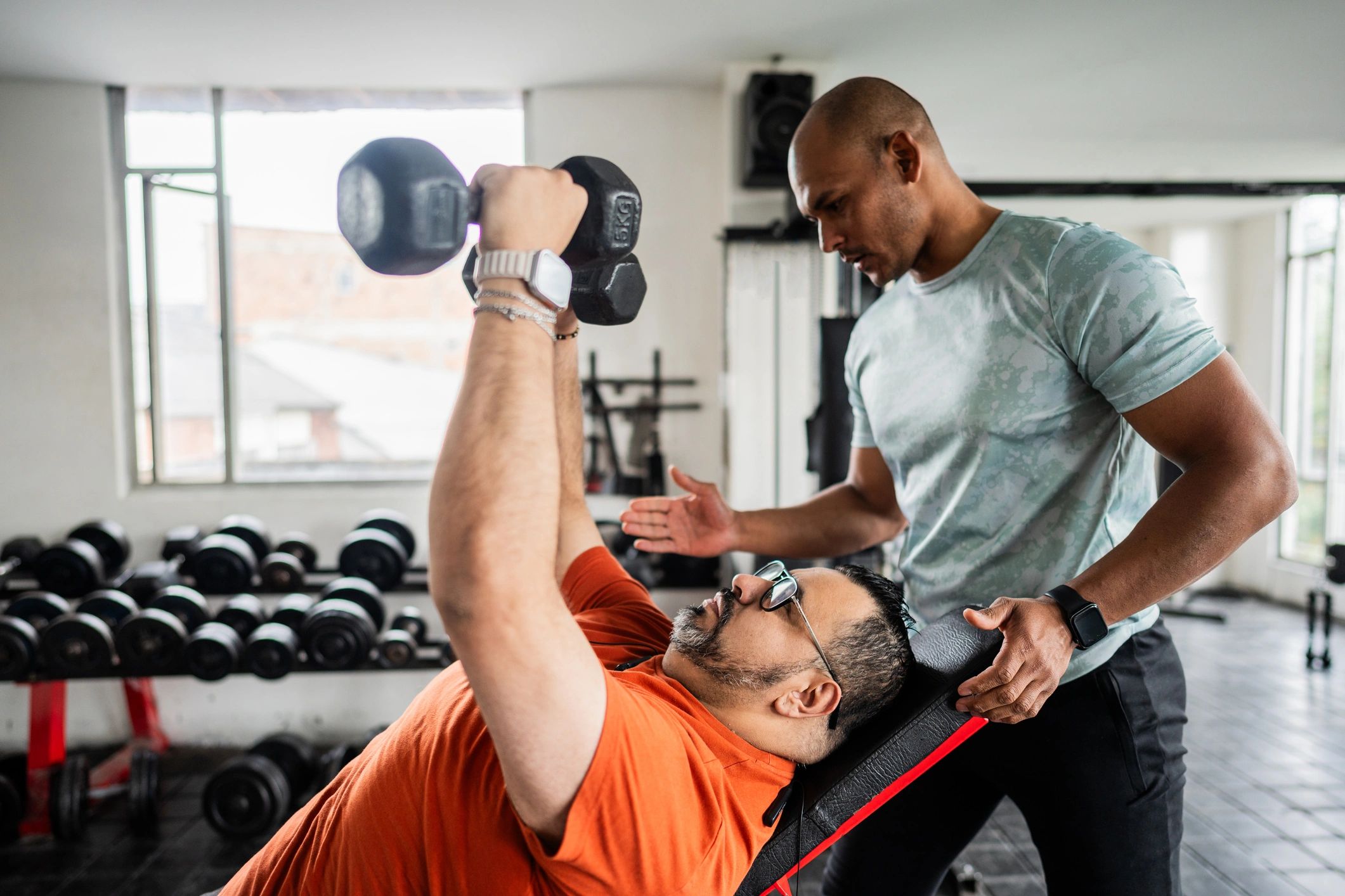 Fitness instructor helping a client with strength training form in a gym