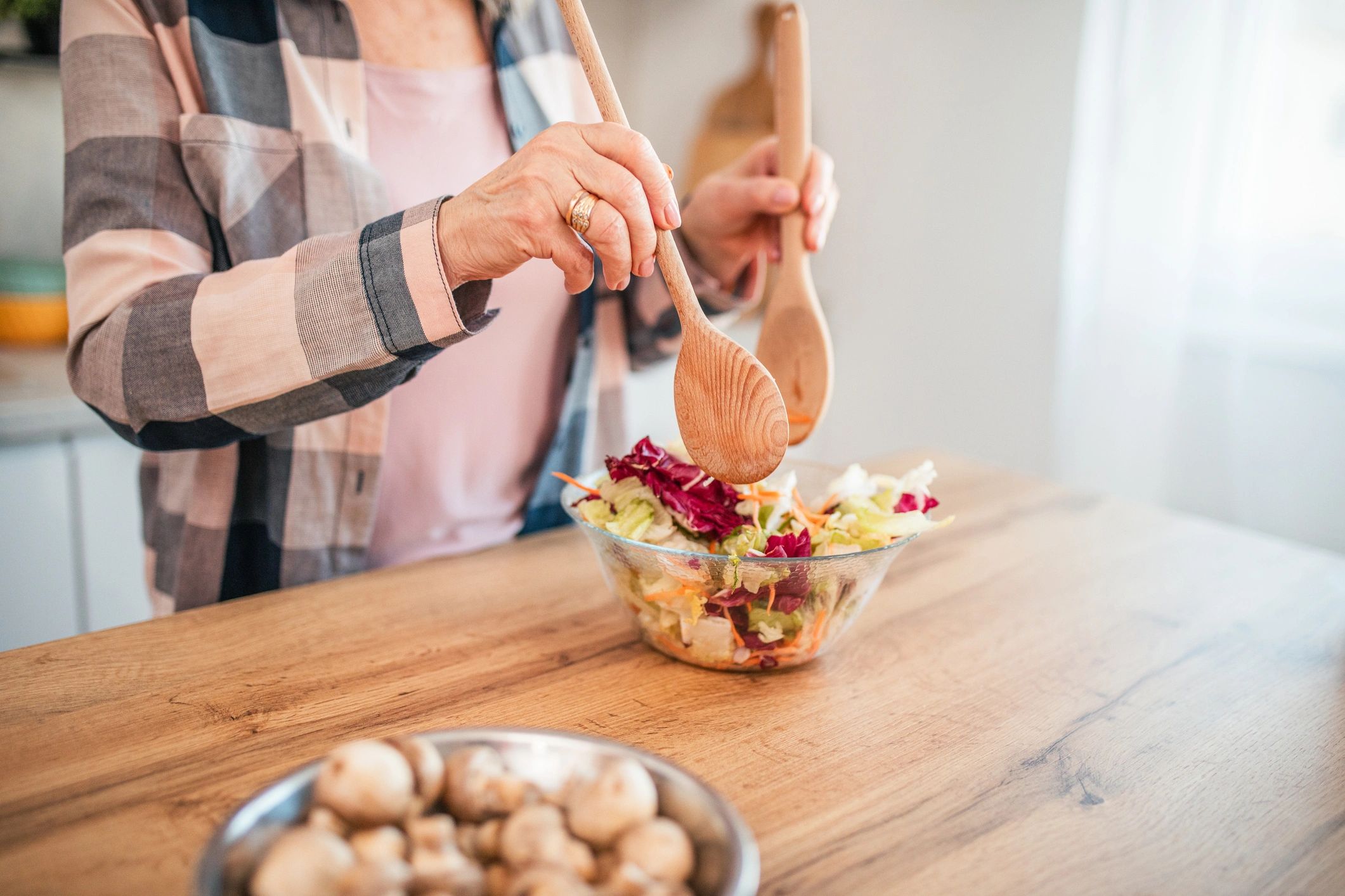Mature woman mixing a fresh salad in a bowl